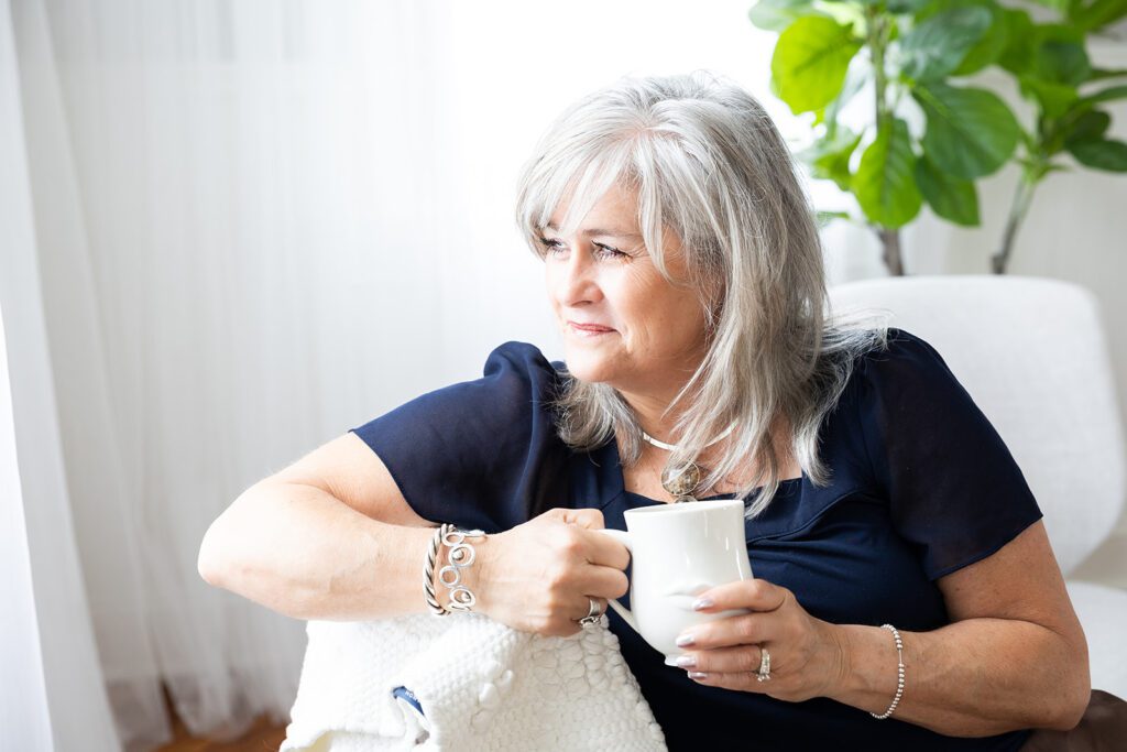 photo of intuative coach holding coffee and thoughtfully looking out window